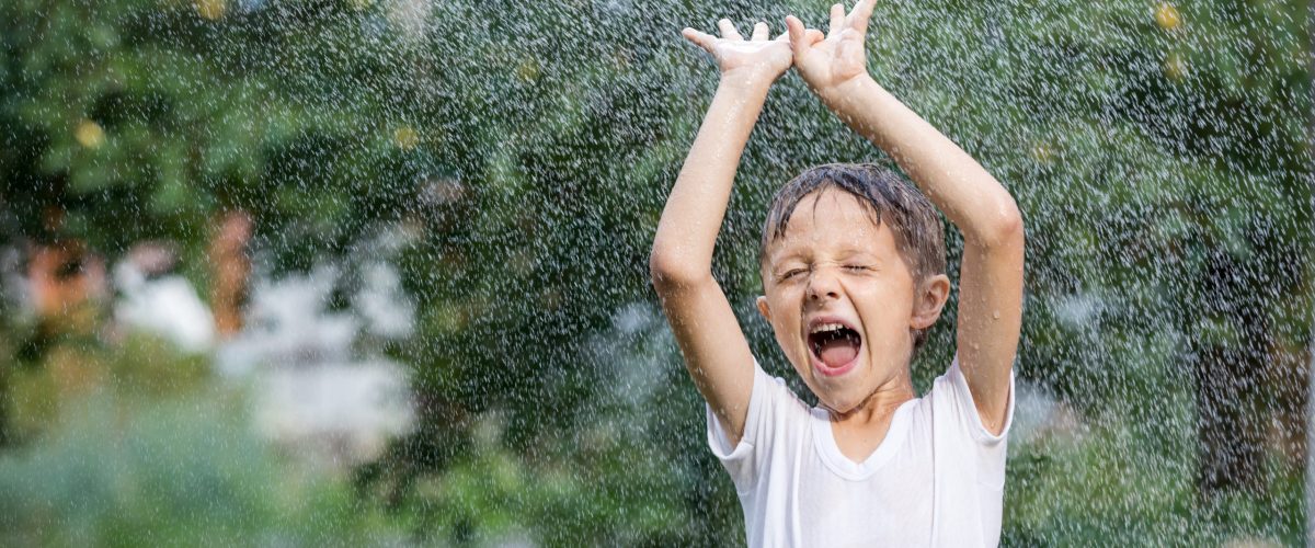 Happy little boy pouring water from a hose. Concept Brother And Sister Together Forever