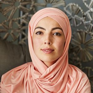 Portrait of young beautiful Muslim woman in light peach hijab smiling at looking at camera